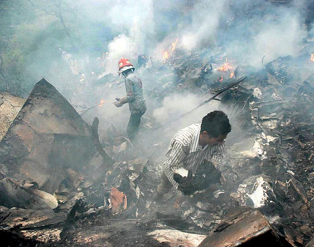In den Trmmern des abgestrzten Flugzeugs suchen Helfer nach den Leichen.   | Foto: dpa