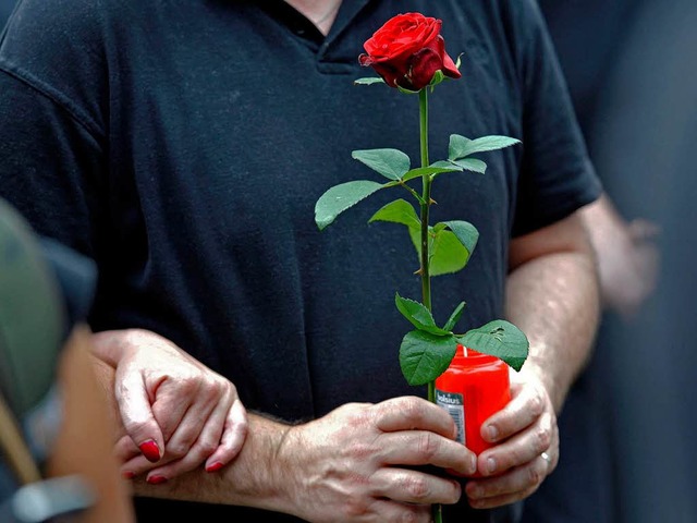 Zeichen der Trauer, Zeichen der Liebe:...n Grablicht und eine Rose in der Hand.  | Foto: dpa