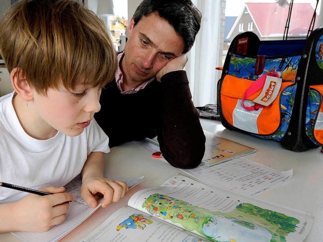 Ein Vater hilft seinem Sohn bei den Hausaufgaben.   | Foto: ddp