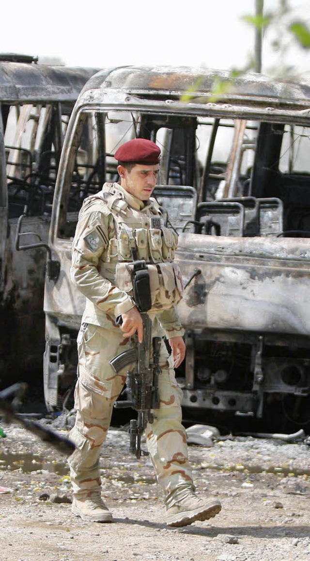 Ein Soldat inspiziert am Sonntag ausgebrannte Fahrzeuge.   | Foto: AFP