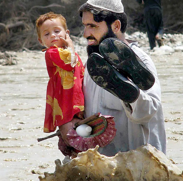 Ein Vater watet mit seiner Tochter durch die Fluten.  | Foto: dpa