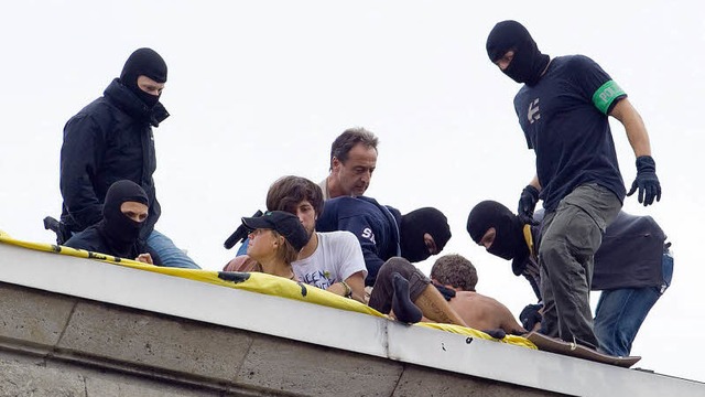 Polizisten mit Tarnkappen holen sieben Demonstranten vom Dach des Nordflgels.    | Foto: dpa