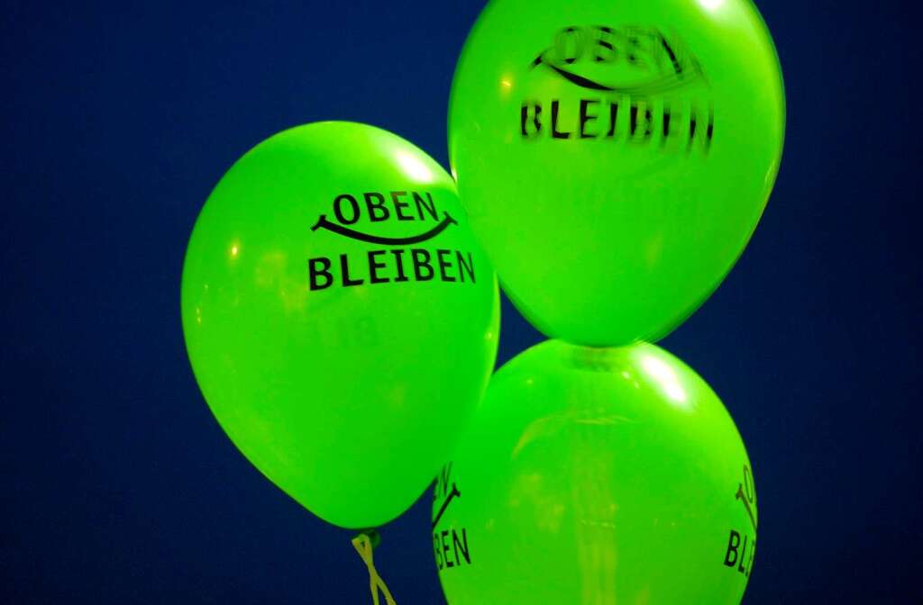 Luftballons mit der Aufschrift "Oben bleiben" werden am Freitagabend in Stuttgart whrend einer Kundgebung auf dem Schlossplatz hochgehalten.