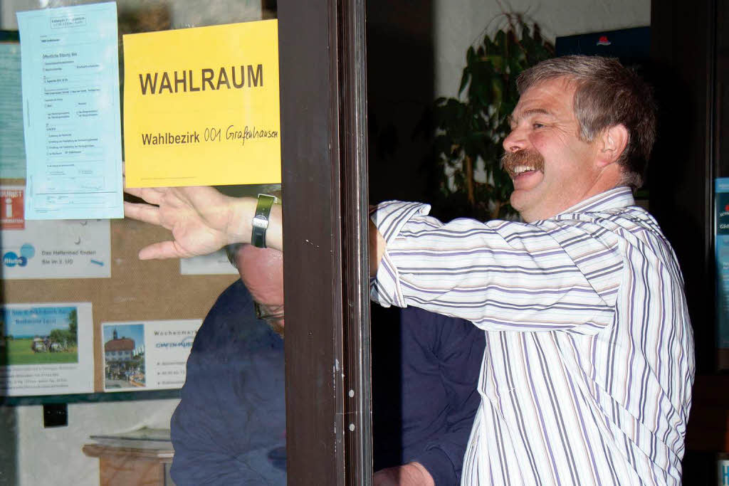 Josef Gatti (rechts) und Roland Strittmatter bringen am Haus des Gastes das Schid "Wahllokal 001" an