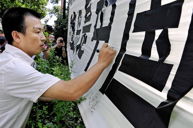 Ein chinesischer Demonstrant signiert ...211; fr die Freilassung des Kapitns.  | Foto: afp