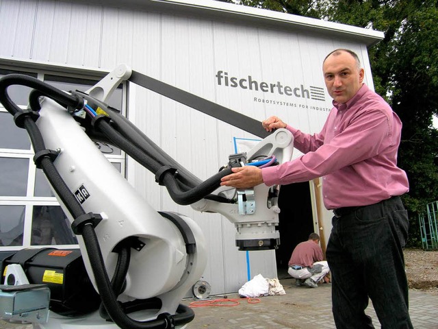 Anlagenbauer Roland Fischer mit einem Roboter vor seiner neuen Halle.   | Foto: Michael Haberer