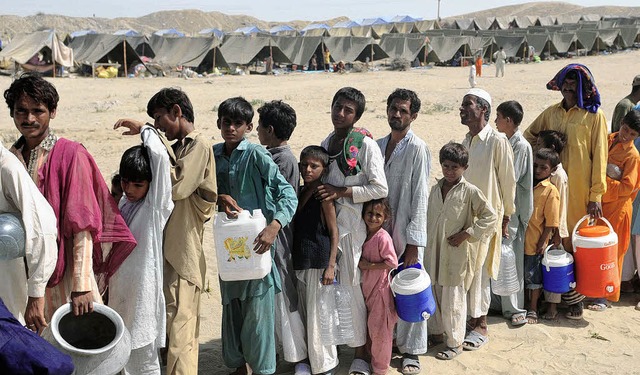 Die Bewohner eines Zeltlagers in Pakis...en darauf, dass Wasser verteilt wird.   | Foto: AFP