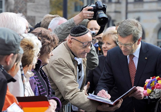 Prsident Christian Wulff spricht bei ...it Brgern, hinter ihm die Kanzlerin.   | Foto: DPA