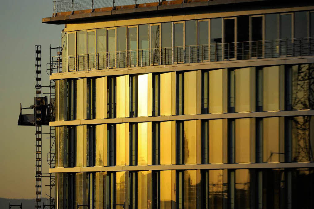 Die Sonne geht unter und taucht eine Fassade am Fahnenbergplatz in goldenes Licht