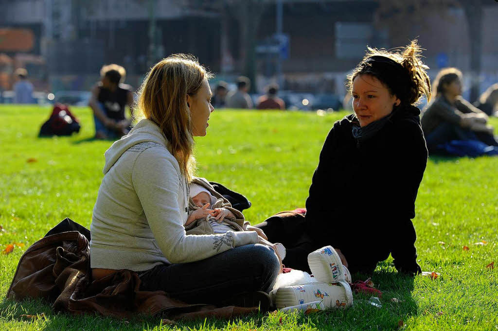 Am Nachmittag wrmt die sonne zwei Frauen auf der Wiese vor dem Kollegiengebude II der Uni.