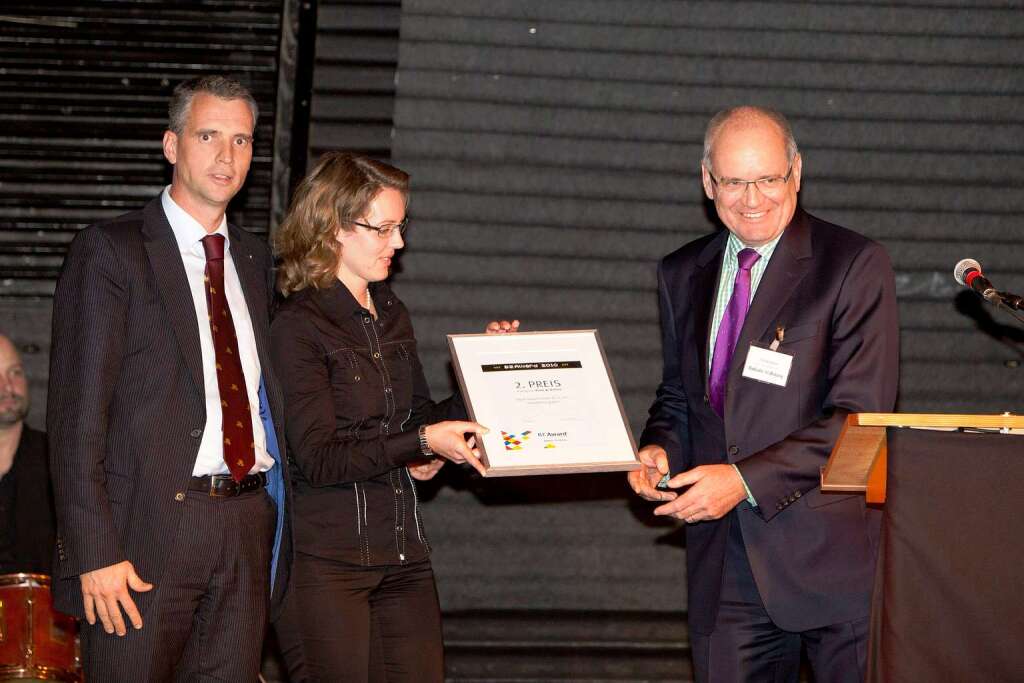 Susan und Thomas Nosch (r.) vom gleichnamigen Optiker nehmen den 2. Preis freudig von Laudator Prof. Thomas Breyer-Maylnder entgegen.