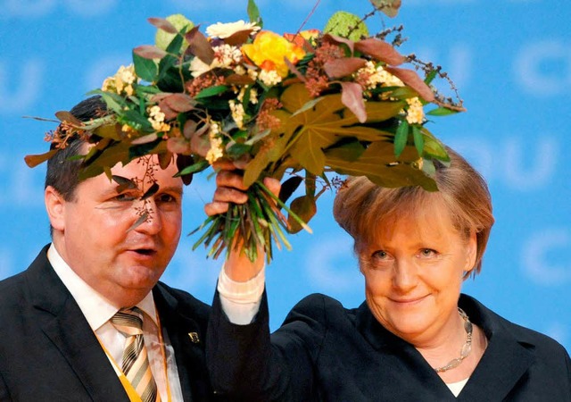 Zusammenhalten unterm Blumenstrau, de...wirkt: Angela Merkel und Stefan Mappus  | Foto: dpa