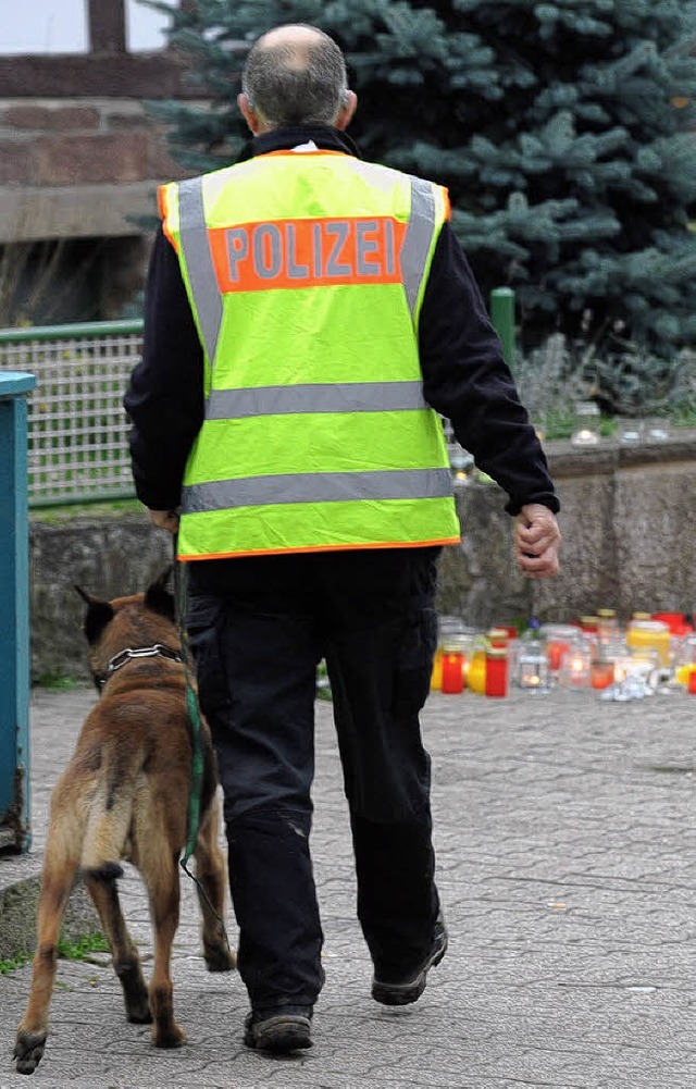 Ein Polizist mit Sprhund in der Nhe der Fundstelle der beiden Leichen   | Foto: dpa