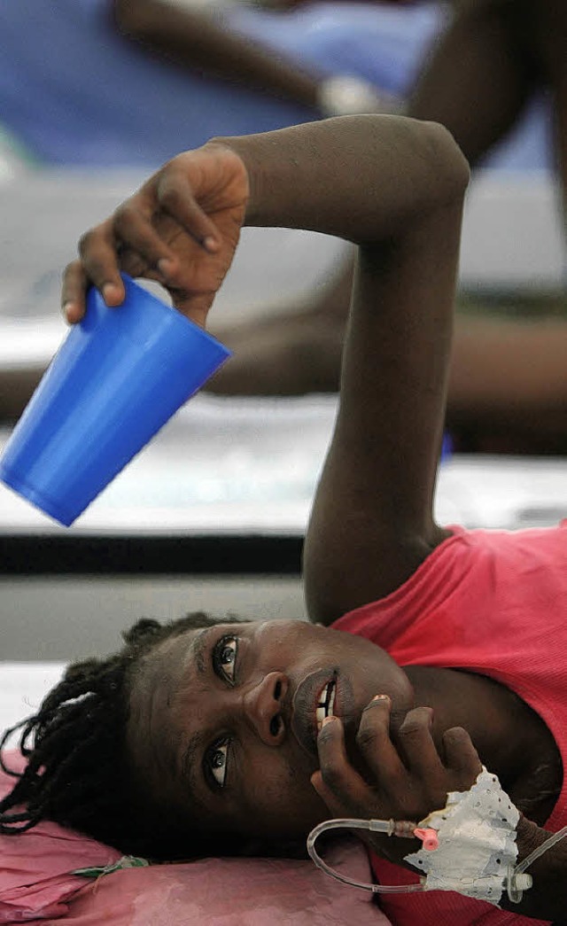 Eine Cholerakranke bittet in Haiti einen Helfer um Wasser.   | Foto: afp