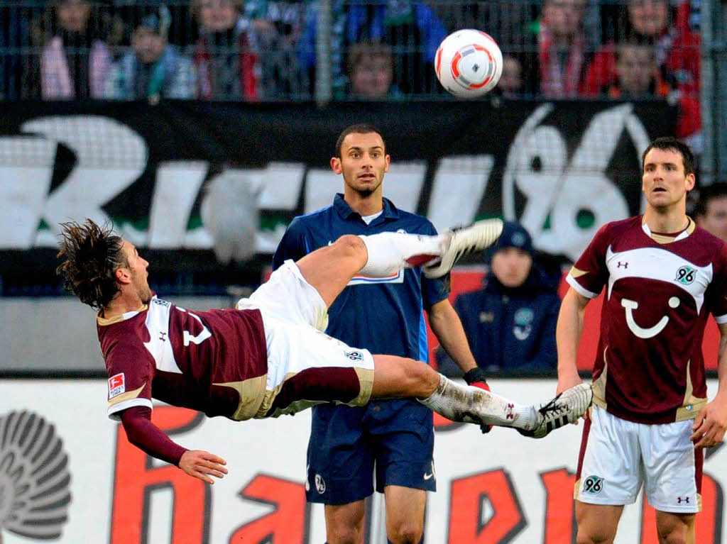 Hannovers Christian Schulz (l) klrt den Ball gegen vor dem Freiburger mer Toprak und seinem Mannschaftskollegen Mario Eggimann (r).