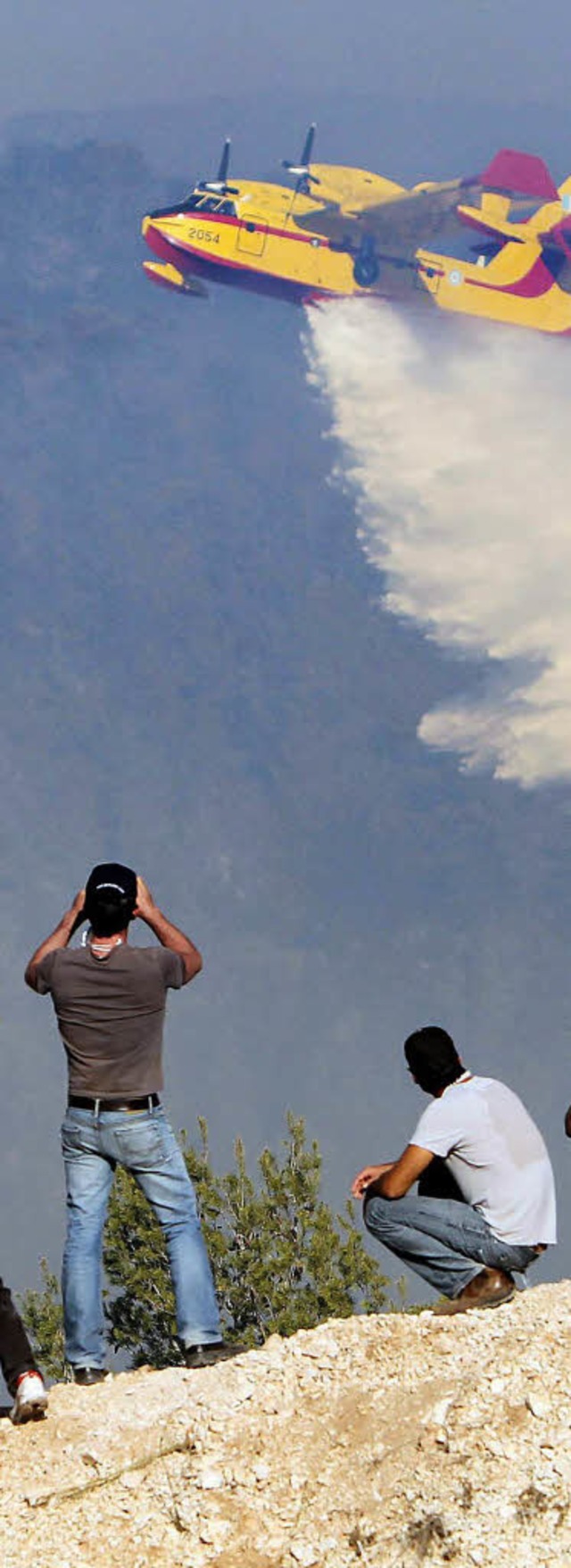 Mnner schauen einem Lschflugzeug bei Haifa zu.  | Foto: dpa