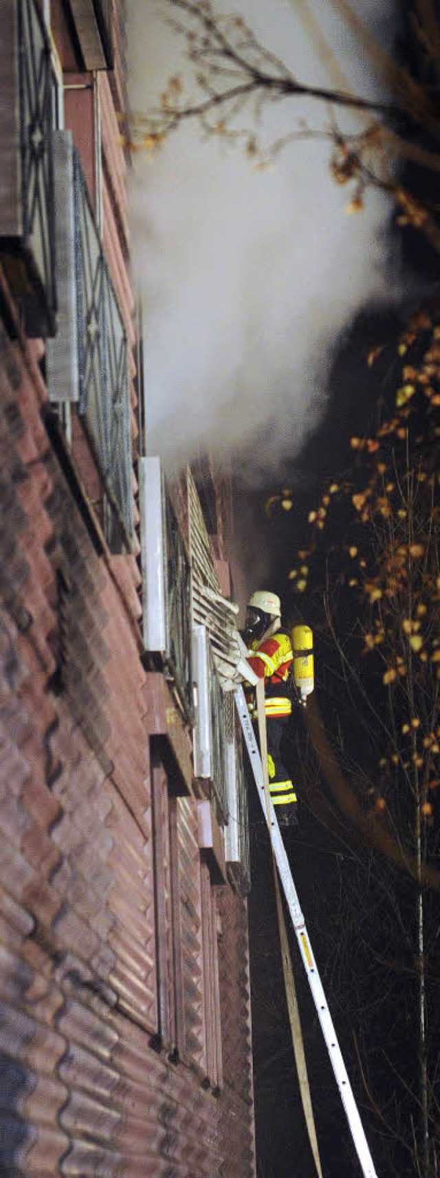 Mit Atemschutz dringt ein Feuerwehrmann ber die Leiter zum Brandherd vor.  | Foto: dpa