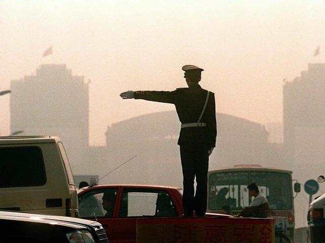 Ein Polizist regelt im vom Smog geplagten Peking den Verkehr.   | Foto: AFP