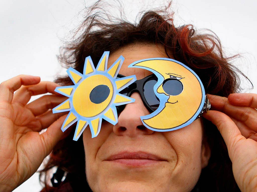 Eine Frau schaut in der Nhe von Schwerin durch eine selbst gebaute Sonnenfinsternisbrille.