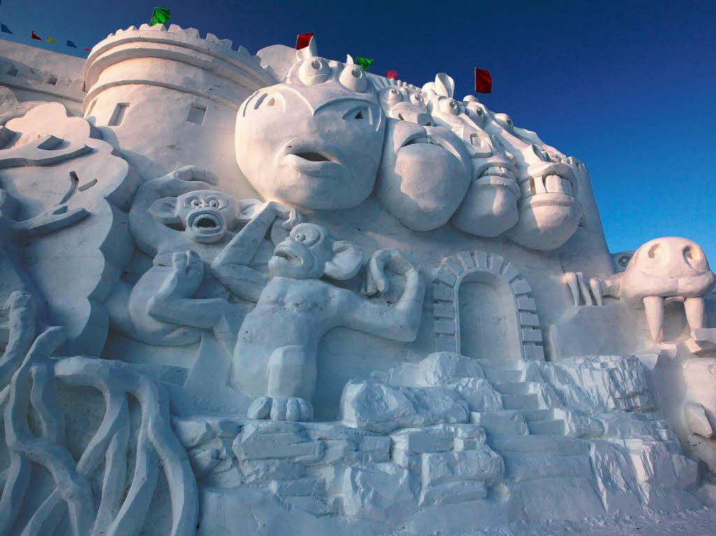 Diese Schneeskulptur zeigt Affen und andere Tiere auf einer Burg.