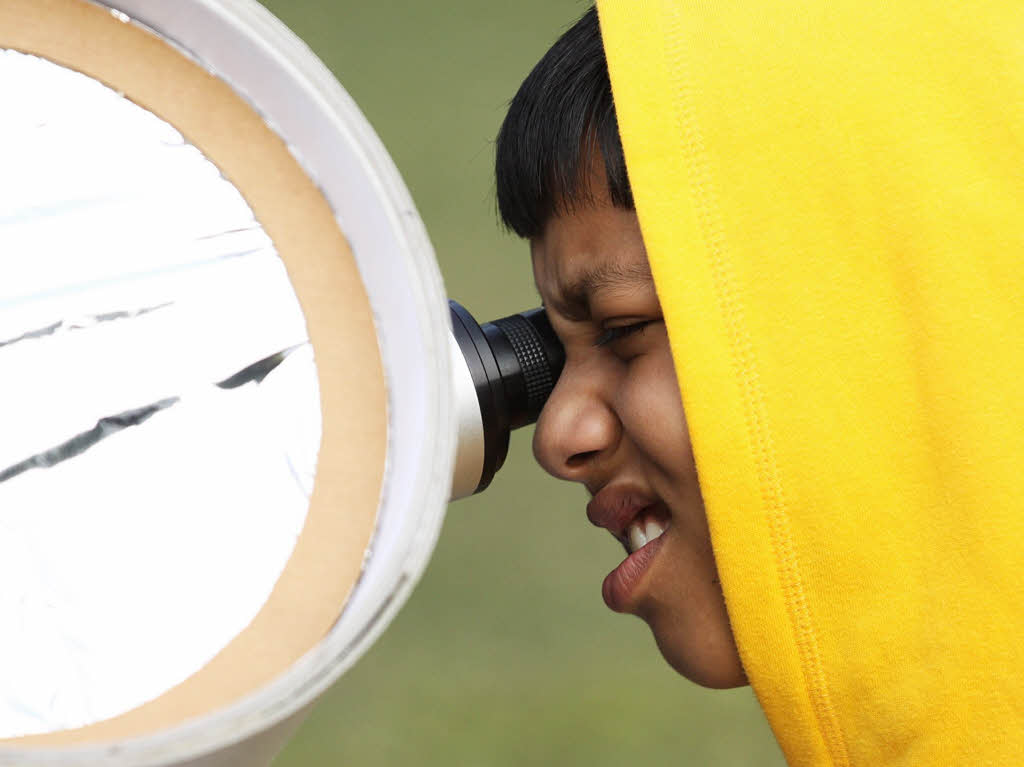 Ein Kind in Indien schaut sich die Sonnenfinsternis durch ein Teleskop an.