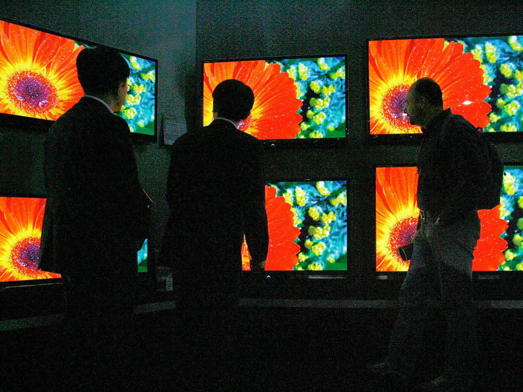 Besucher vor einer Bildschirmwand von Sharp.