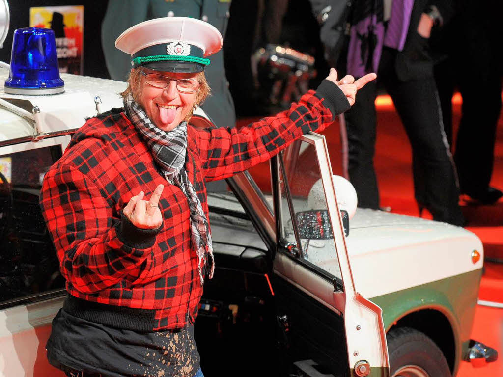 Schauspieler Martin Semmelrogge posiert an einem DDR-Polizeiauto.
