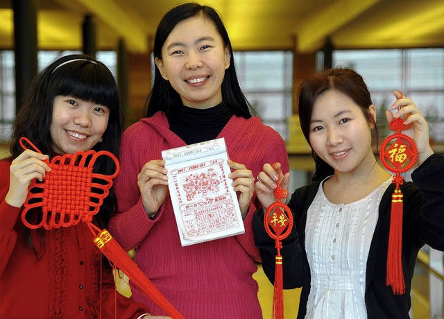 Ladies in red: Yuan Yang, Sen Yang und... (von links) mit Festdeko und Kalender  | Foto: Ingo Schneider