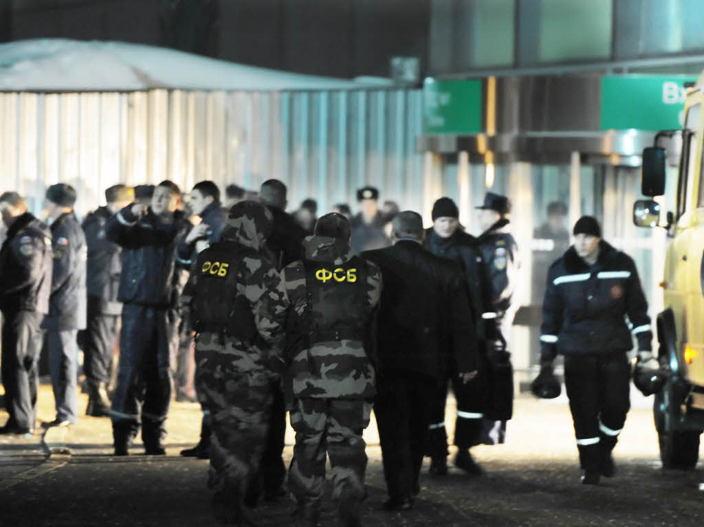 Sprengstoffexperten des russischen Inlandsgeheimdienstes FSB und Polizisten stehen vor dem Flughafen Domodedowo in Moskau.