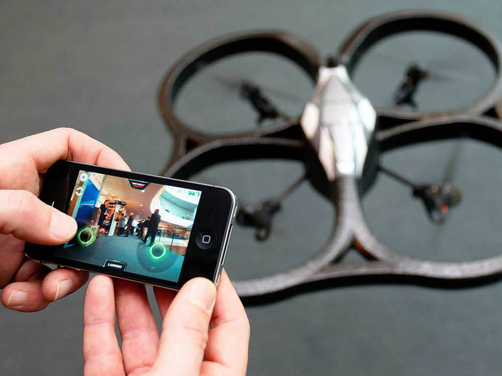 Mittels eines iPhones steuert ein Mitarbeiter einen Quadcopter.