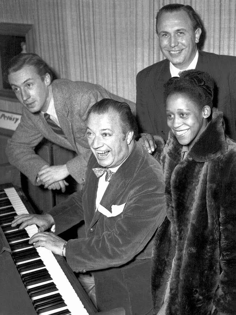 Peter Alexander , der deutsche Pianist und Komponist Peter Kreuder (am Klavier), der Snger Rudi Hofstetter und die sdafrikanische Sngerin Leila Negra (von links nach rechts) feiern 1950 die Ankunft Kreuders in Deutschland.