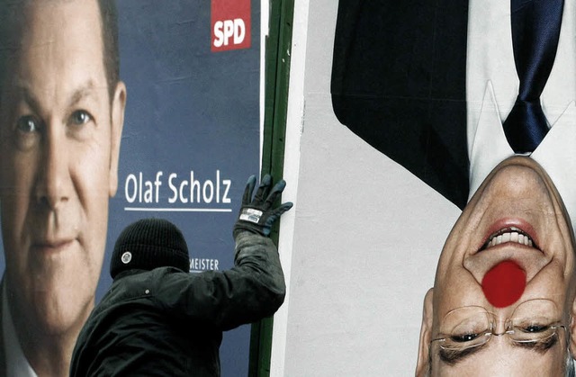 Ein Plakatierer verldt in Hamburg ein...ch das Plakat von Olaf Scholz (SPD).    | Foto: dapd