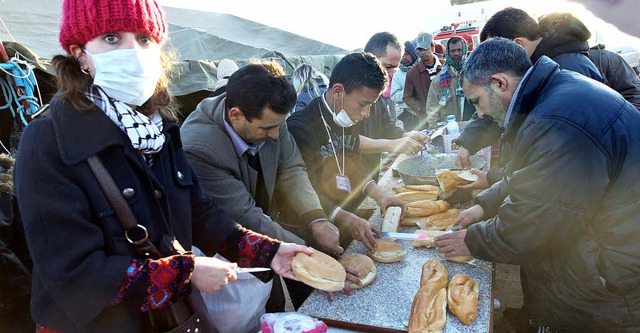 Freiwillige Helfer teilen an der tunes... Brote an Flchtlinge aus Libyen aus.   | Foto: DPA