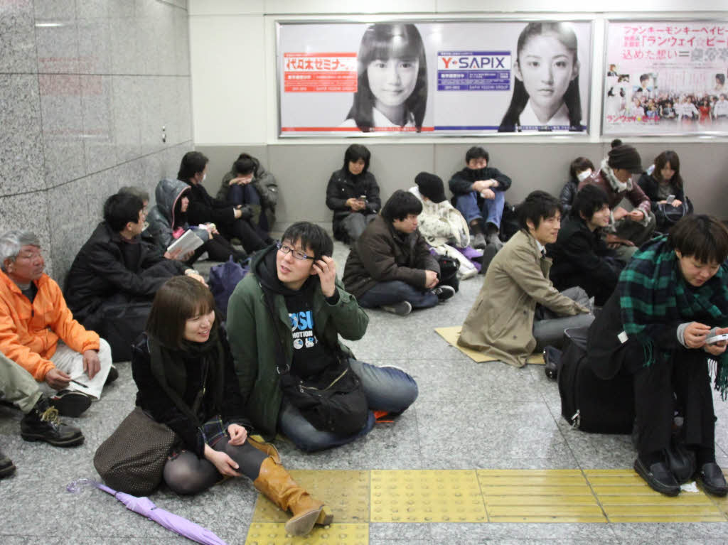 Gestrandete Passagiere sitzen in der Yokohama Station.