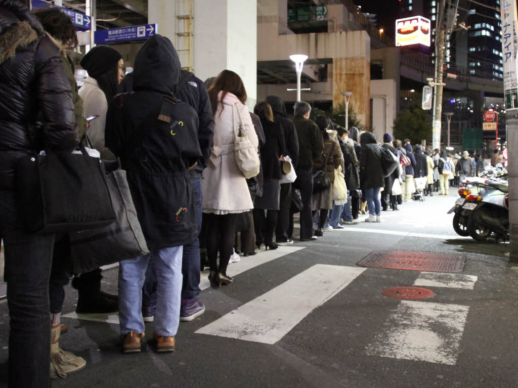 Hunderte Leute stehen Schlange, um in Yokohama ein Taxi zu bekommen.