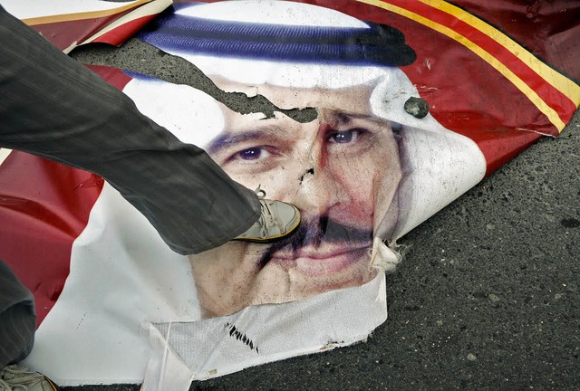 Ein Demonstrant zerstrt ein Plakat de...hen Knigs Hamad bin Issa al-Khalifa.   | Foto: AFP