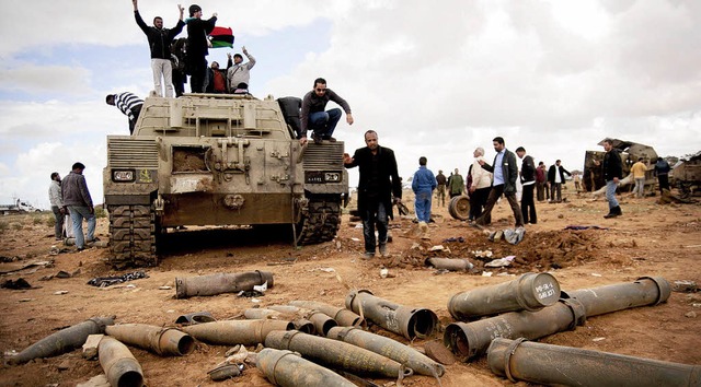 Aufstndische jubeln auf einem Panzer ... Militrflugzeuge beschossen hatten.    | Foto: dpa