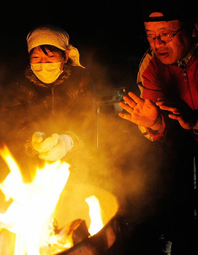 Evakuierte Japaner wrmen sich an einem Feuer.  | Foto: DPA