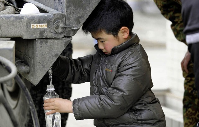 Ein japanischer Junge holt sich  frisches Trinkwasser aus dem Tanklastwagen.  | Foto: AFP