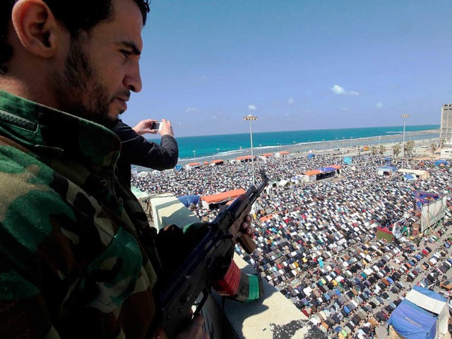 Ein Soldat der Rebellen berwacht das Freitagsgebet am Strand von Bengasi.   | Foto: DPA