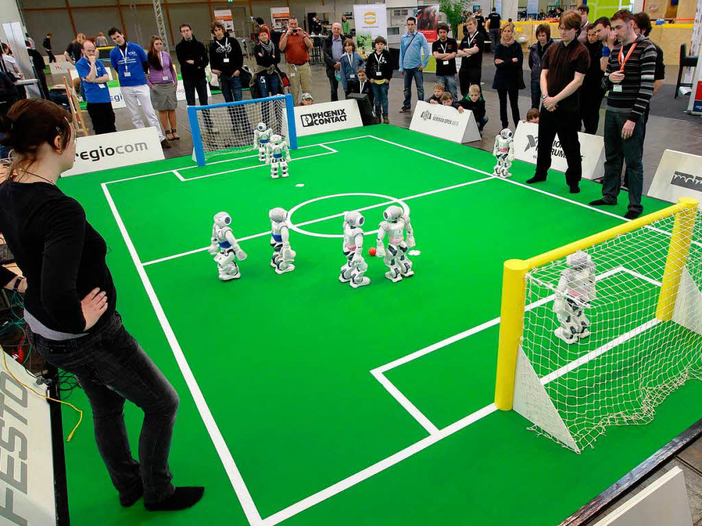 Einige Zuschauer haben sich um das  Spielfeld versammelt.