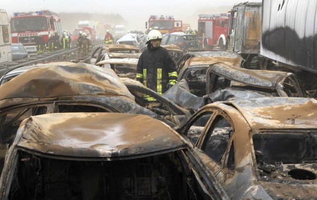 Einsatzkrfte stehen  am Unfallort  in...Rostock zwischen ausgebrannten Autos.   | Foto: dpa