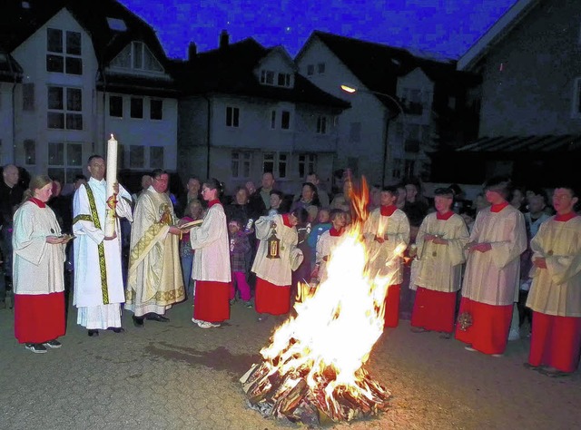 Erstmals wird das Osterfeuer vor der P...noch ziemlich dunkle Kirche getragen.   | Foto: Stefan Heimpel