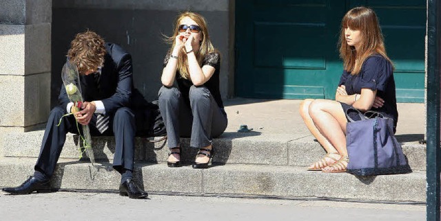 Freunde der Getteten sitzen nach der Beerdigung vor der Kirche in Nantes.  | Foto: AFP/dpa