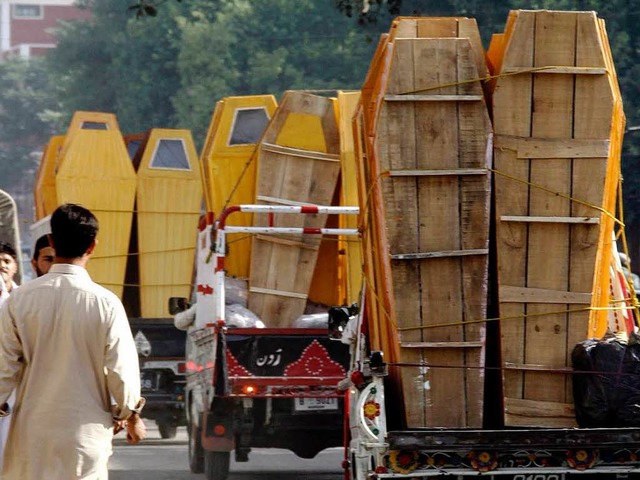 Rettungskrfte bringen Srge an den Ort des Doppelanschlags in Pakistan.  | Foto: dpa