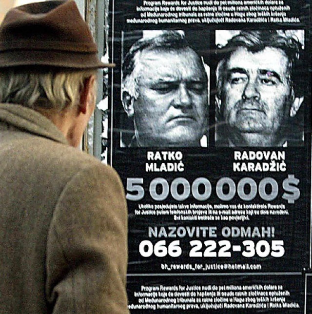 Ein Mann betrachtet 2002 in Sarajevo Fahndungsfotos von Mladic und Karadzic.   | Foto: dpa