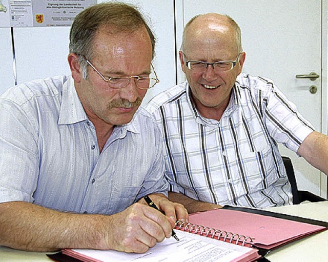 Rolf Karrer sieht Thomas Birlin beim Unterzeichnen zu.   | Foto: Gerigk