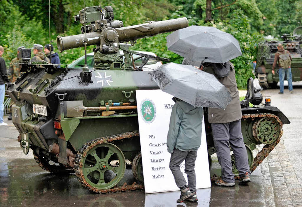 Vater und Sohn schauen sich einen Panzer vom Typ Wiesel  an.