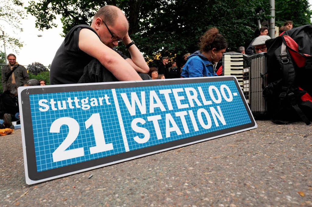 Ein Stuttgart-21-Gegner sitzt mit Protestschild vor einem Bautor.