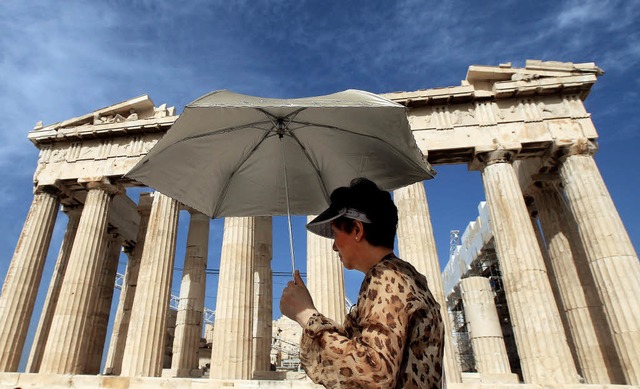 Eine Touristin besucht mit Schutzschirm den Parthenon-Tempel auf der Akropolis.  | Foto: dpa